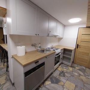 a small kitchen with white cabinets and a sink at U Gumisia in Korbielów