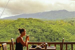 a woman sitting at a table looking at the mountains at Green Coco Suite by AGATA in Nusa Penida