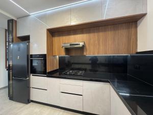 a kitchen with black counter tops and wooden cabinets at Appartement sur villa in Temara