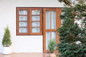 a window on the side of a house with two potted plants at Rungarun Residence in Ratchaburi