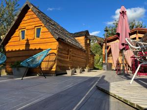 a wooden house with an umbrella and some chairs at La cabane enchantée in Hudiviller