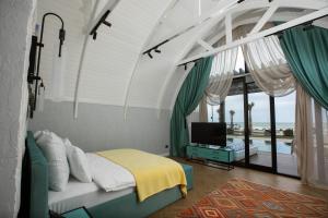 a bedroom with a bed and a television and a balcony at CaspiMayr Retreat Beach Resort in Baku