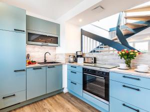a kitchen with blue cabinets and a staircase at Prora - Ferienwohnung mit Waschmaschine - Meeresrauschen Dachterrasse in Binz