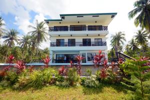 a building with palm trees in front of it at Anapuro Elnido in El Nido