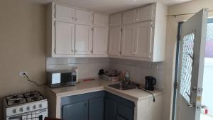 a kitchen with white cabinets and a sink and a microwave at Harmony Guest House in Bridgetown
