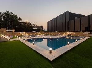 a large swimming pool with lights and a building at Assembly By The Democracy in Nashik