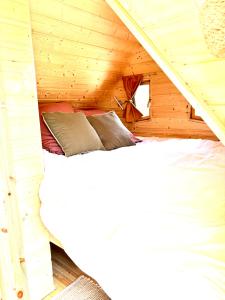 a bed in a wooden cabin with a roof at La cabane enchantée in Hudiviller