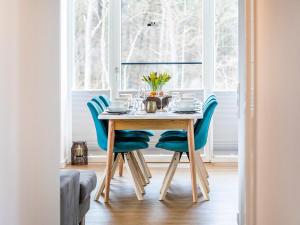 a dining room table with blue chairs in front of a window at Prora - Apartment mit Sauna - Baltic Sunset in Binz