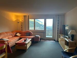 a living room with a couch and a large window at Disentis-Mustér Ski Apartment in Disentis