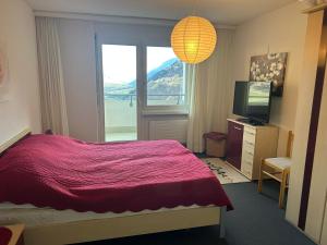 a bedroom with a red bed and a window at Disentis-Mustér Ski Apartment in Disentis