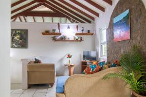 a living room with a couch and a tv at La Caye - Ocean View Villa in Calibishie