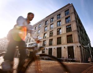 un homme faisant du skateboard devant un bâtiment dans l'établissement Hotel AMANO Rooms & Apartments, à Berlin