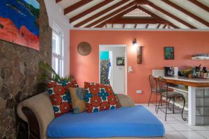 a living room with a blue couch and a kitchen at La Caye - Ocean View Villa in Calibishie