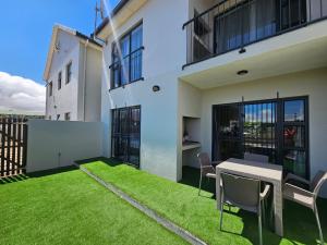 a balcony with a table and chairs and grass at Nemesia Court in Durbanville