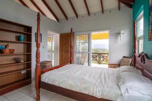 a bedroom with a bed and a balcony at La Caye - Ocean View Villa in Calibishie