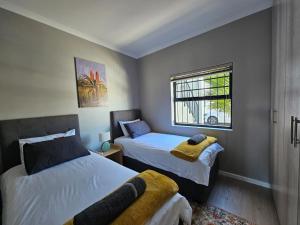 a bedroom with two beds and a window at Nemesia Court in Durbanville
