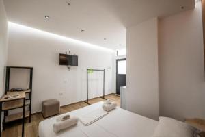 a white bedroom with a bed and a television on the wall at Azure Bay Resort in Sarandë
