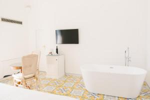 a bathroom with a tub and a table and a television at Villa Principe Giovanni in Positano