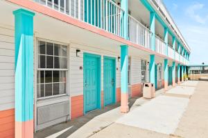 a row of brightly colored buildings with blue doors at Moonlight Inn Hotel O Hattiesburg, MS in Hattiesburg