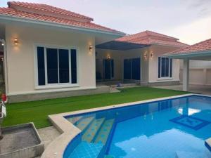 a villa with a swimming pool in front of a house at The Natphop pool villa Meeting Pool Villa in Cha Am