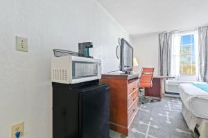 a room with a bed a microwave and a desk at Moonlight Inn Hotel O Hattiesburg, MS in Hattiesburg