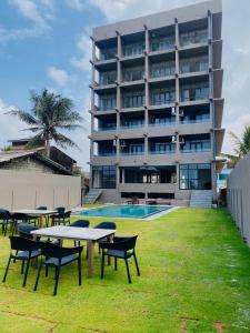 a building with tables and chairs in front of a pool at Trident Sea Hotel in Negombo