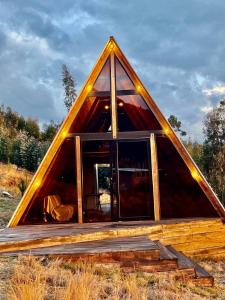 a frame house with a large window in a field at Conga Lodge Cabana Alpina in La Conga
