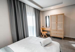 a bedroom with a white bed and a desk at Nima Suites Corfu in Marathias
