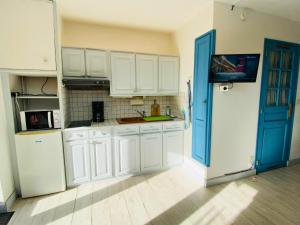 a kitchen with white cabinets and a blue door at Studio aux Sources de la Chabanne in Saint-Hilaire-les-Courbes +30 photos
