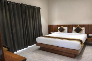 a bedroom with a large bed with black curtains at Hotel Shree Abhishek in Bārāmati