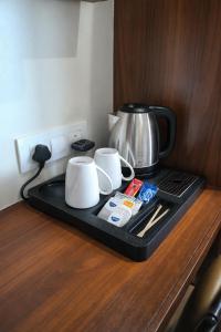 a tray with two cups and a tea kettle on a counter at Hotel Shree Abhishek in Bārāmati
