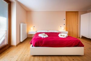 a bedroom with a large red bed with two towels at La Marmote Albergo Diffuso di Paluzza Aip in Paluzza