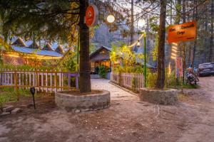 a group of trees with a fence and a house at Himtrek Riverside Camps, Kasol in Kasol
