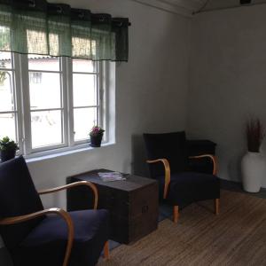 a living room with two chairs and a table and windows at Stugan på Skårby in Ystad