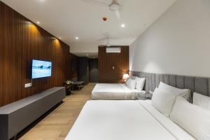 a hotel room with two beds and a couch at Assembly By The Democracy in Nashik