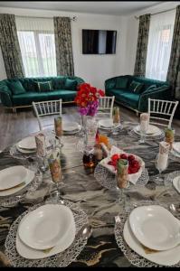 a dining room table with plates and flowers on it at Casa AIDA in Peşteana