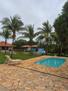 a swimming pool with a chair and palm trees at Pousada Akonxego in Olímpia