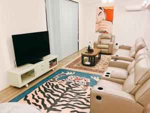 a living room with a couch and a television and a zebra rug at SEA BASE Onna in Onna