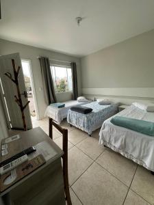 a hotel room with two beds and a desk at Pousada Guanumbi in Morretes