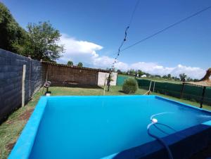 a blue swimming pool in a yard with a fence at Cabañas Rústicas Entre Montañas in Tunuyán