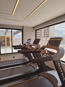 a gym with treadmills and ellipticals and windows at Apartamento completo e elegante no centro de Pouso Alegre in Pouso Alegre