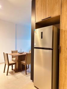 a kitchen with a table and a stainless steel refrigerator at Apartamento completo e elegante no centro de Pouso Alegre in Pouso Alegre