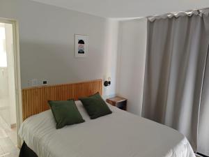a bedroom with a bed with two green pillows at Entre Montañas - Vista Calma in Potrerillos