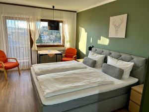 a bedroom with two beds and an orange chair at Hotel Panorama in Waldachtal