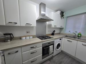 a kitchen with white cabinets and a stove top oven at Cozy Gem Luxury House in Marston Green