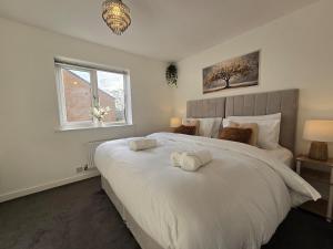 a bedroom with a large white bed with towels on it at Cozy Gem Luxury House in Marston Green