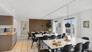 a dining room with white tables and black chairs at Villavilla 148 - Ebeltoft, Østjylland in Ebeltoft