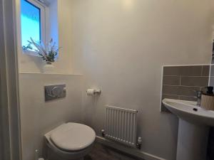 a bathroom with a toilet and a sink and a window at Cozy Gem Luxury House in Marston Green +29 photos