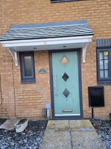 a blue door on a brick building with a television at Cozy Gem Luxury House in Marston Green
