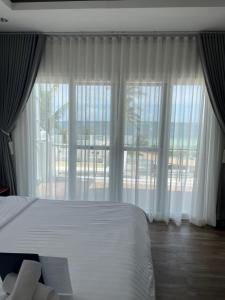 a bedroom with a bed and a large window at Maykenn Beach-Cafe Bar and Restaurant in Bantayan Island